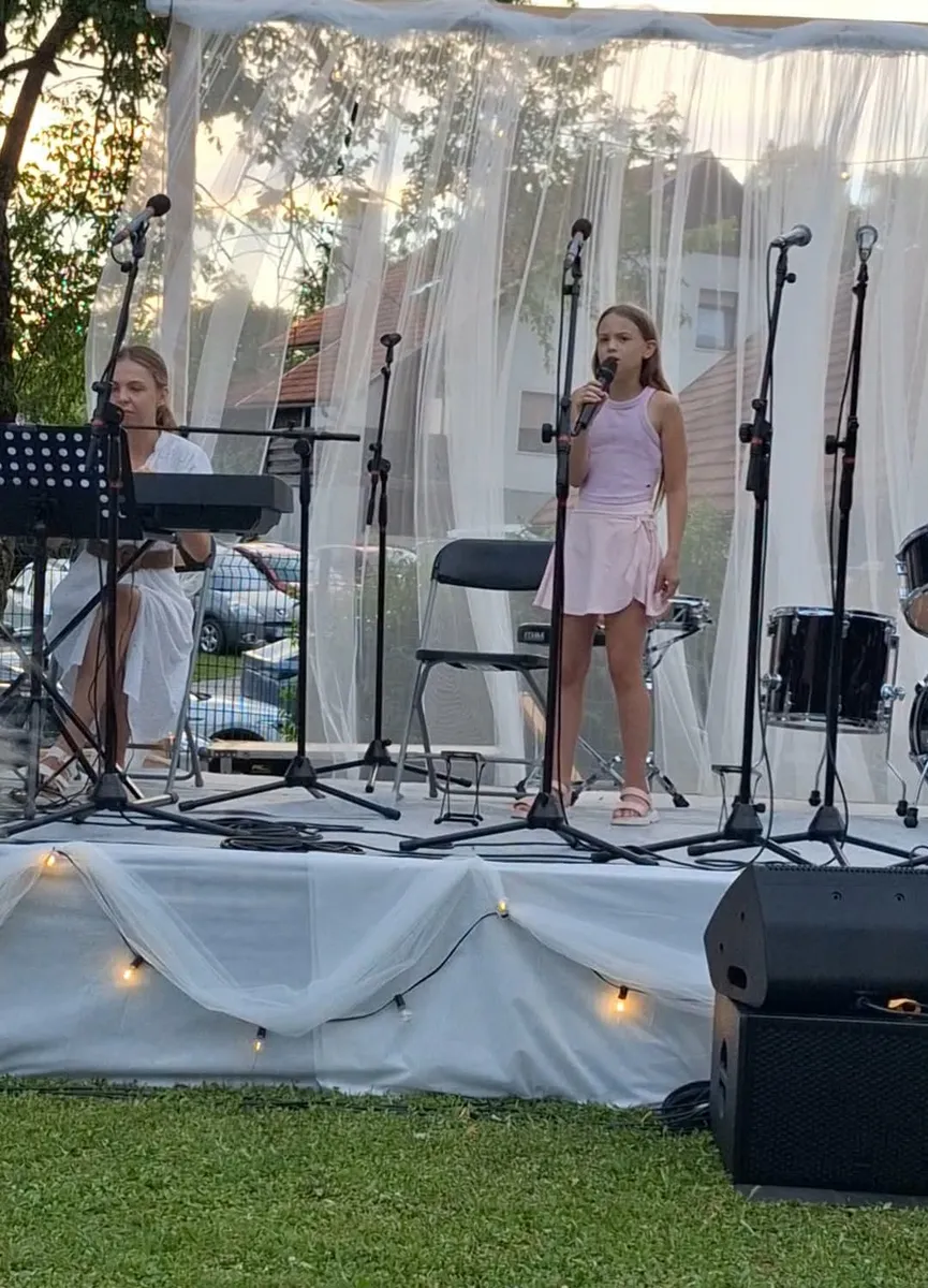 Mlada pevka nastopa ob klavirski spremljavi.